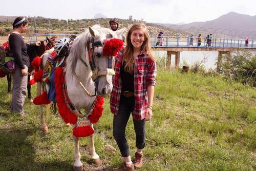 Alumna Kala Willette standing next to a horse dressed in traditional garb